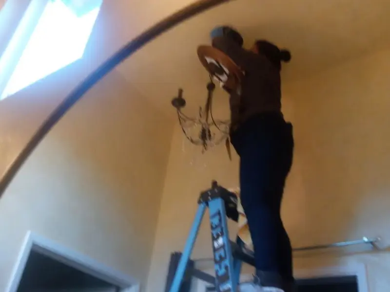 Electrician installing a chandelier in a Lakeland residence